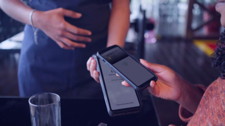 Woman using smartphone to make contactless payment