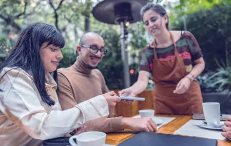 SoftPOS_Payment by card on smartphone_Woman at restaurant_0.png