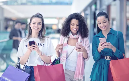 Three girls shopping in mall with cell phones in their hands