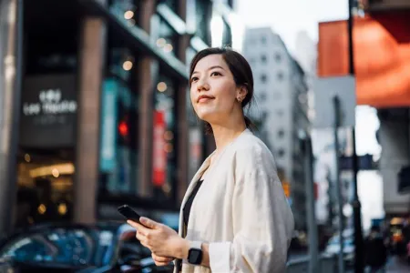 Woman using smartphone in APAC city, representing the shift to digital payments and modern payment platforms